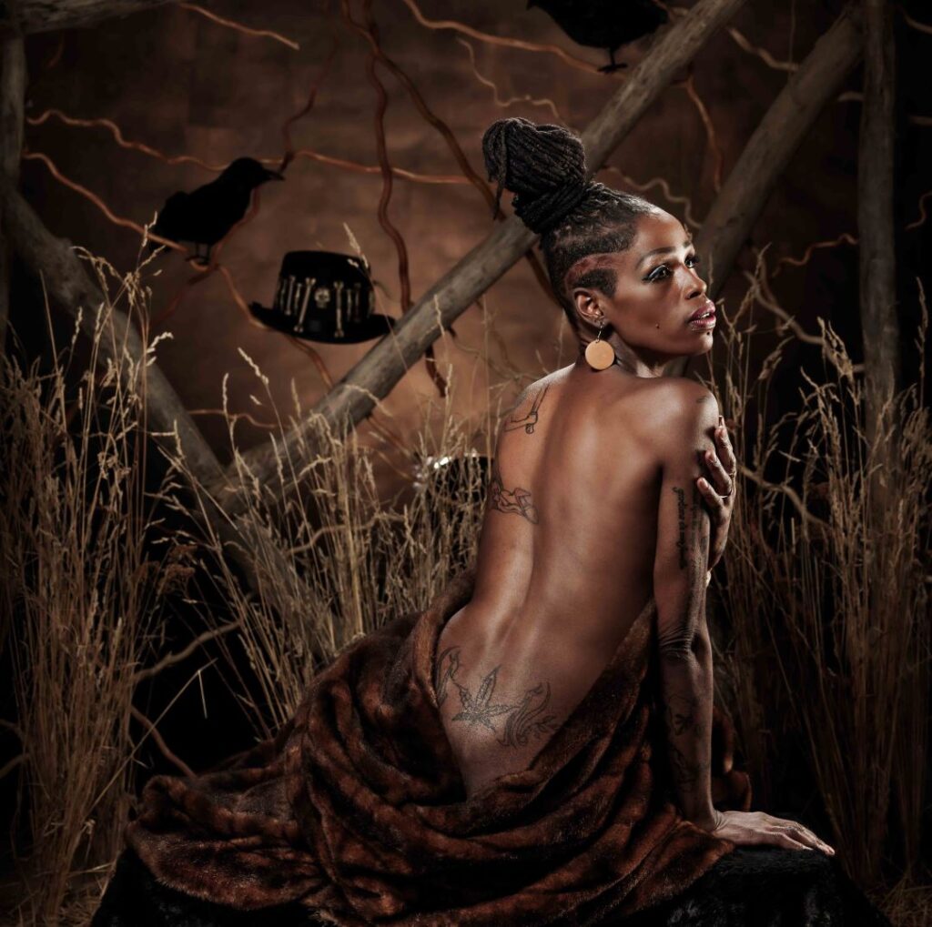 a woman with tattoos on her body sitting in a forest